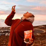 Women enjoying spicy cherry + almonds chocolate superfood clusters on top of volcano in Hawaii