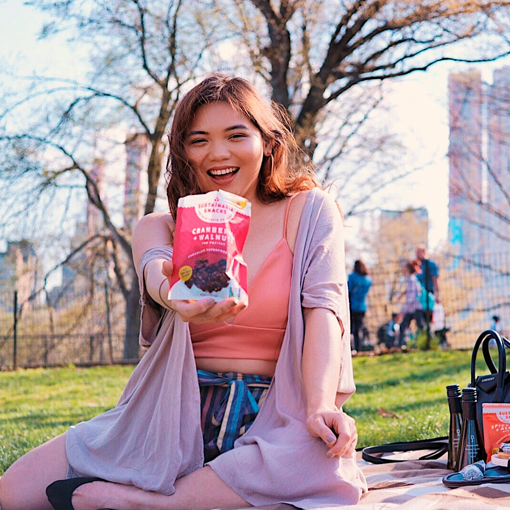 Young women in central park holding cranberry + walnuts chocolate superfood clusters
