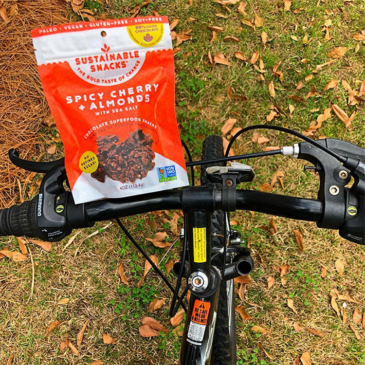 Spicy Cherry + almonds bag of chocolate superfood clusters on bike riding on grass
